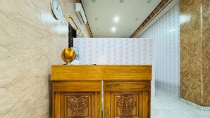 A reception desk with a clock, an air conditioning unit, and a decorative lamp. - Tamastu House Sunter (Jakarta)