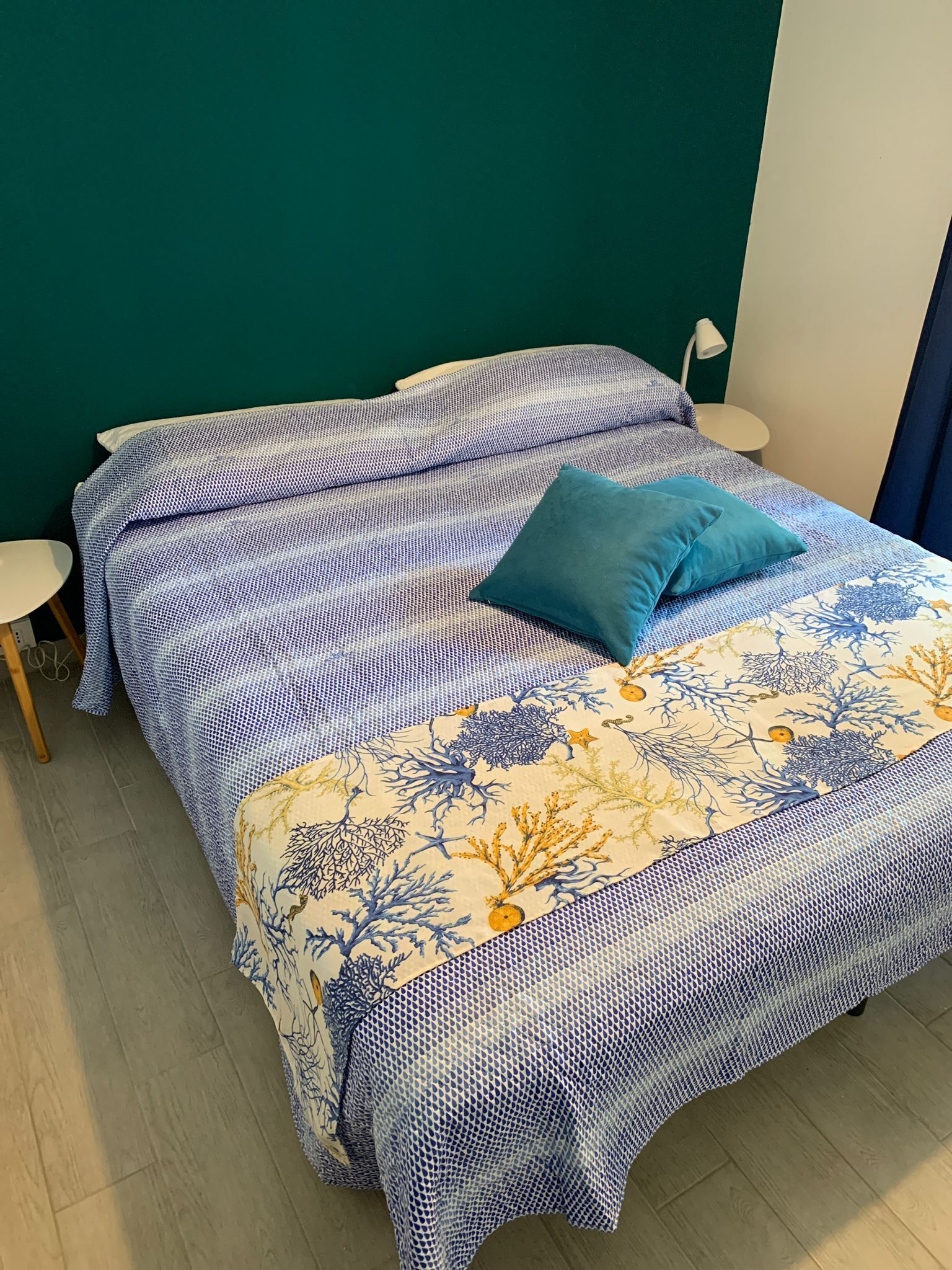 Ein Bett mit einem gemusterten Überwurf und einem blauen Kissen.