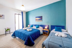 A hotel room with two beds, a nightstand, a small table with a plant, and a painting on the wall.