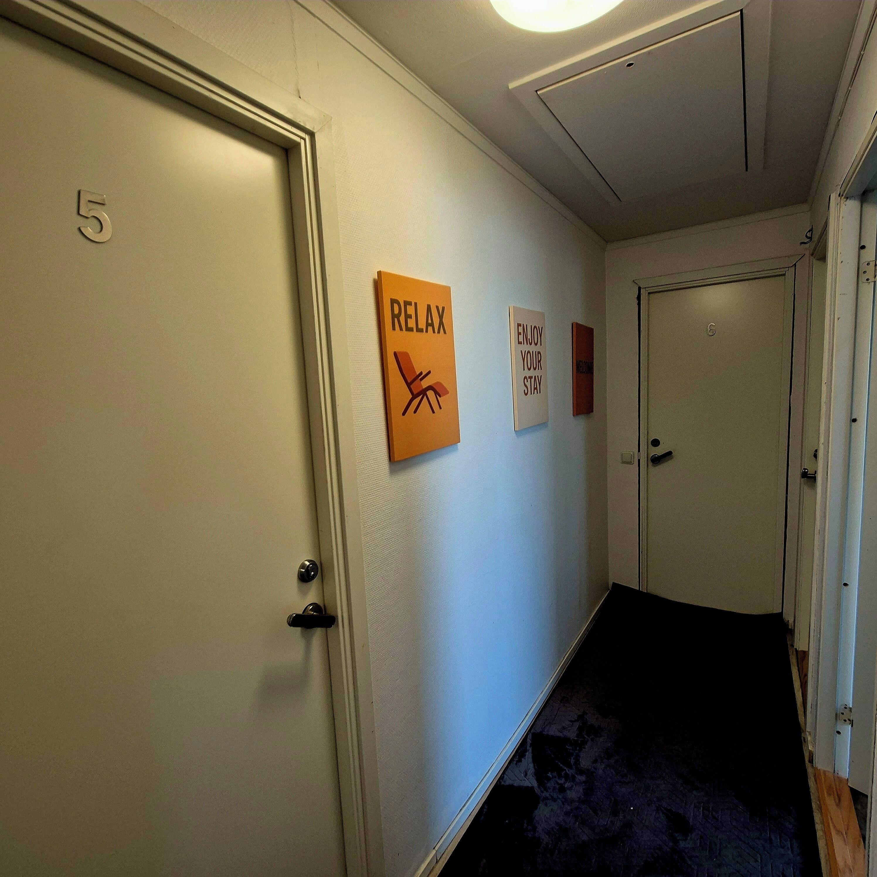 A hallway with a door labeled '5', a 'RELAX' sign, and a 'WELCOME' sign on the wall.