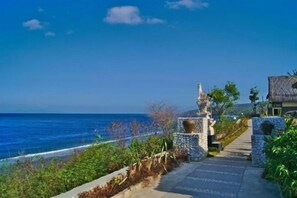 A coastal pathway leading to a stone structure with a view of the sea. - Song Cang Bungalow (Bali)