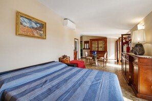 Une chambre à coucher avec un lit, un bureau, une chaise, une armoire et un tableau accroché au mur.