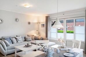 A modern living room with a sofa, coffee table, and dining table set for tea.