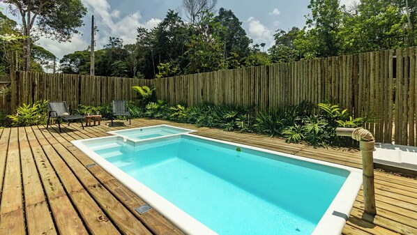 A rectangular swimming pool with a wooden deck surrounding it. - Itaka Studio Piscina Hidro e Quadra em Arraial (Porto Seguro)