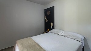 A bedroom with a bed, a nightstand, and a wall-mounted decoration. - Itaka Studio Piscina Hidro e Quadra em Arraial (Porto Seguro)