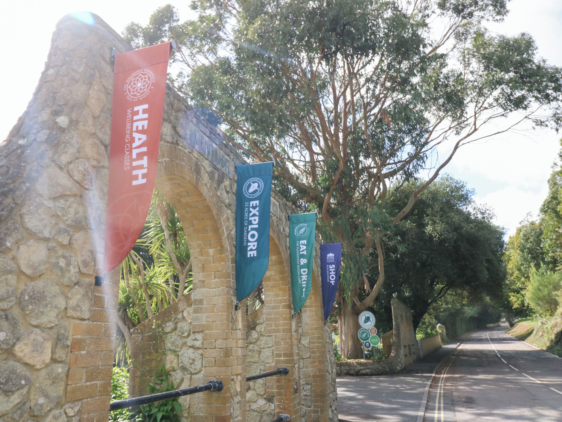 A stone archway with banners for health, explore, eat & drink, and shop.