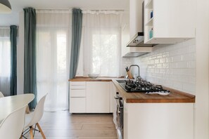 Een moderne keuken met witte kasten, een houten aanrecht en een gasfornuis.