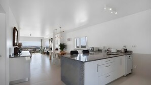Una cocina moderna con una isla central, muebles blancos y una zona de comedor con vistas.