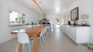Una cocina moderna con una mesa de madera y sillas blancas, un ventanal y vistas al exterior.