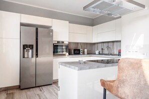 Une cuisine moderne dotée d’appareils électroménagers en acier inoxydable, de meubles blancs et d’un îlot central.