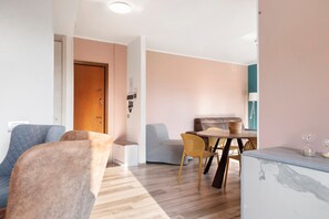 Un salon moderne comprenant un canapé, des fauteuils, une table à manger et un coin cuisine.
