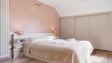 A bedroom with a bed, bedside tables, a nightstand, a lamp, and a wardrobe.