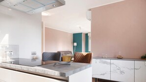 Une cuisine moderne dotée d’un plan de travail en marbre, d’un four encastré et d’une armoire blanche agrémentée de détails en marbre.