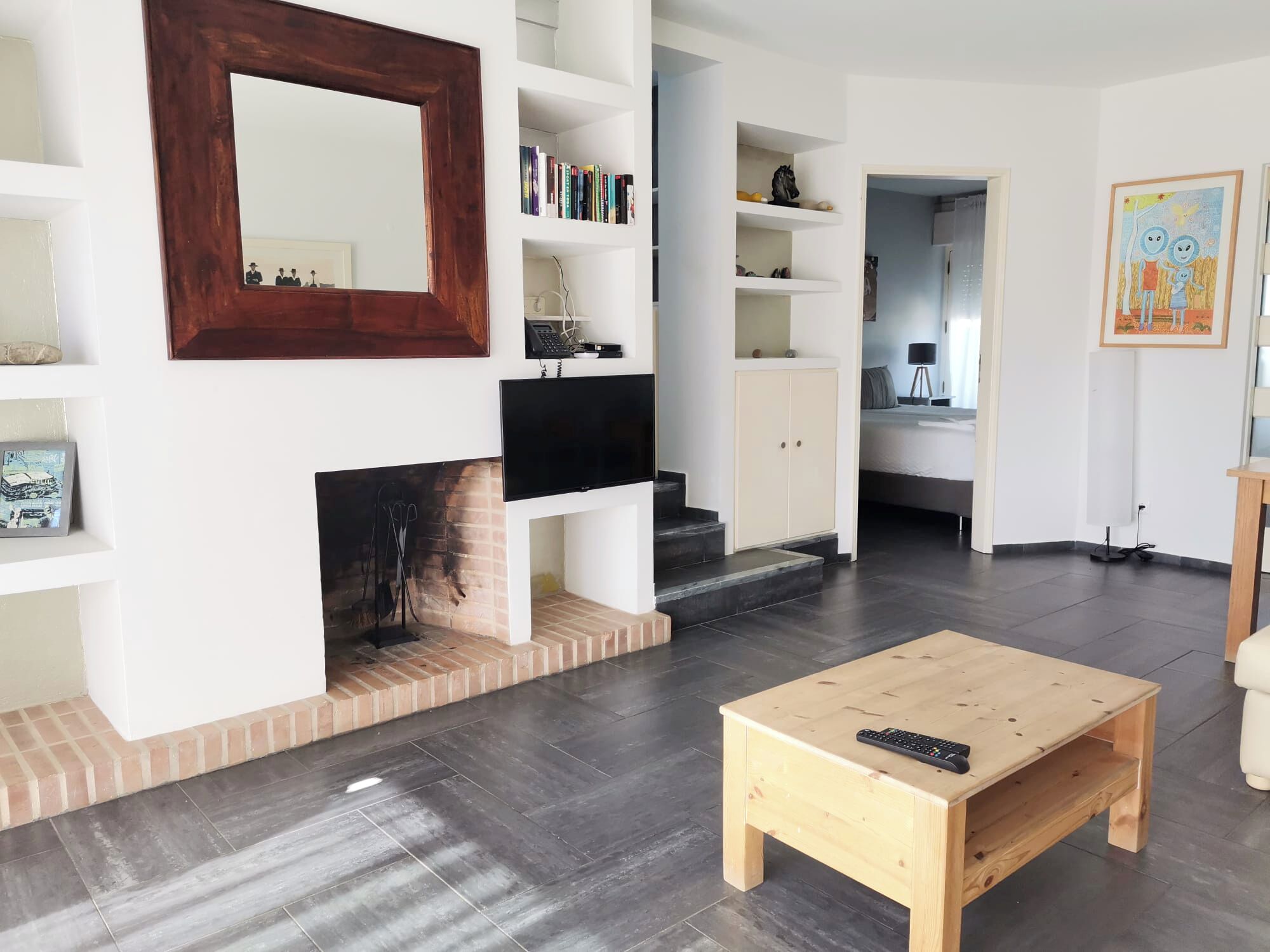 A modern living room with a fireplace, a TV mounted on the wall, and a wooden coffee table.