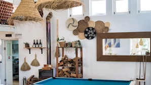 A billiards table labeled 'BILHARSUL' in a room with rustic decor, including woven baskets, wooden shelves, and a variety of plants. - Sea View Terrace Wellness Apartment - Duna Parque Group (Odemira)