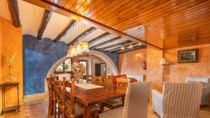 A dining area with a wooden table and chairs, a chandelier, and a fireplace. - Casa Rural Somni Compartit – Tradition and Comfort in Sant Martí de Maldà (Sant Martí de Maldà)