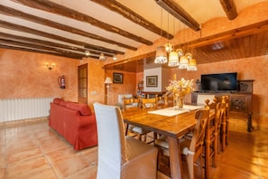 Un comedor con mesa de madera, sillas y televisor.