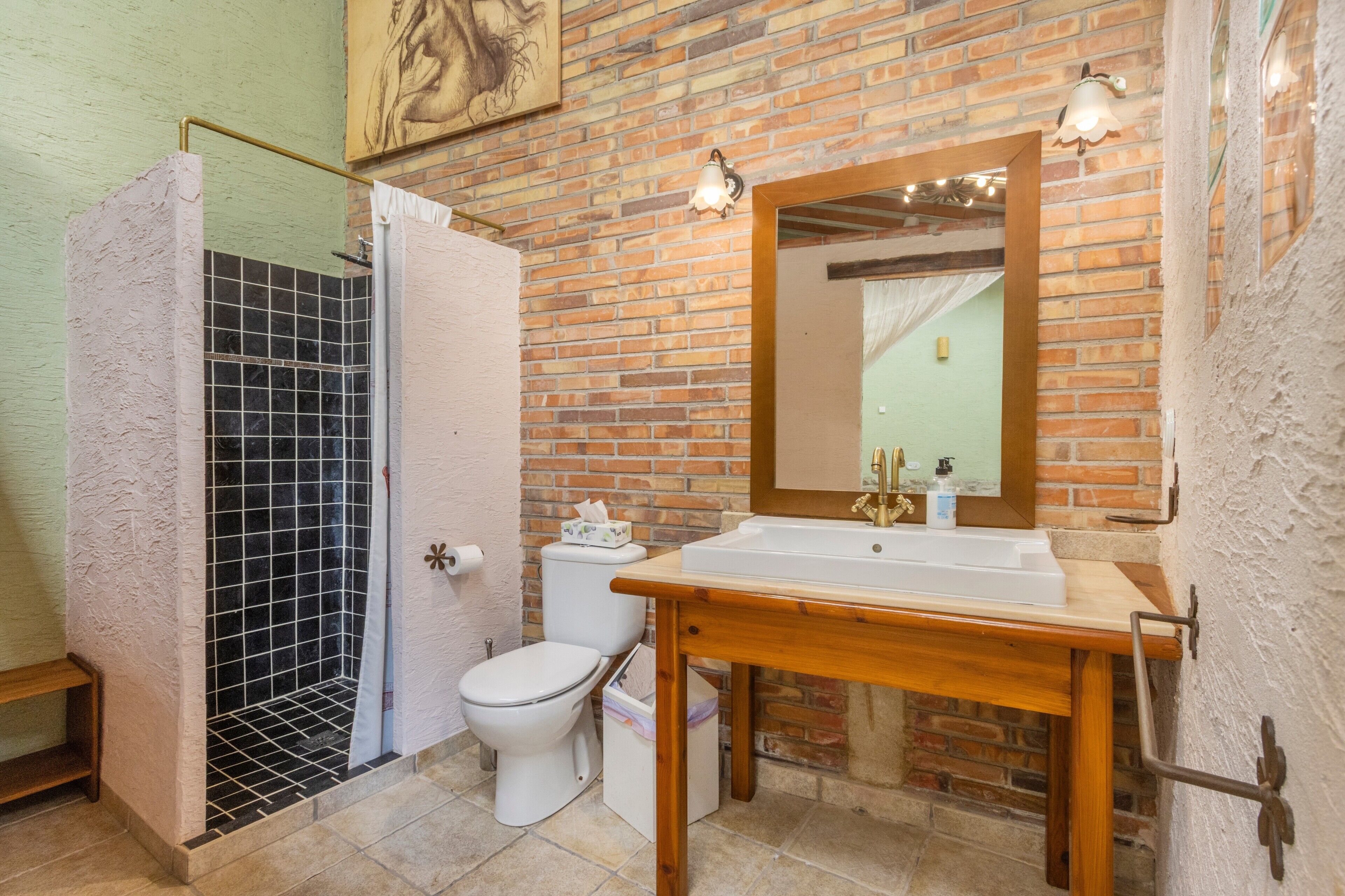 Een badkamer met douche, toilet, wastafel en spiegel.