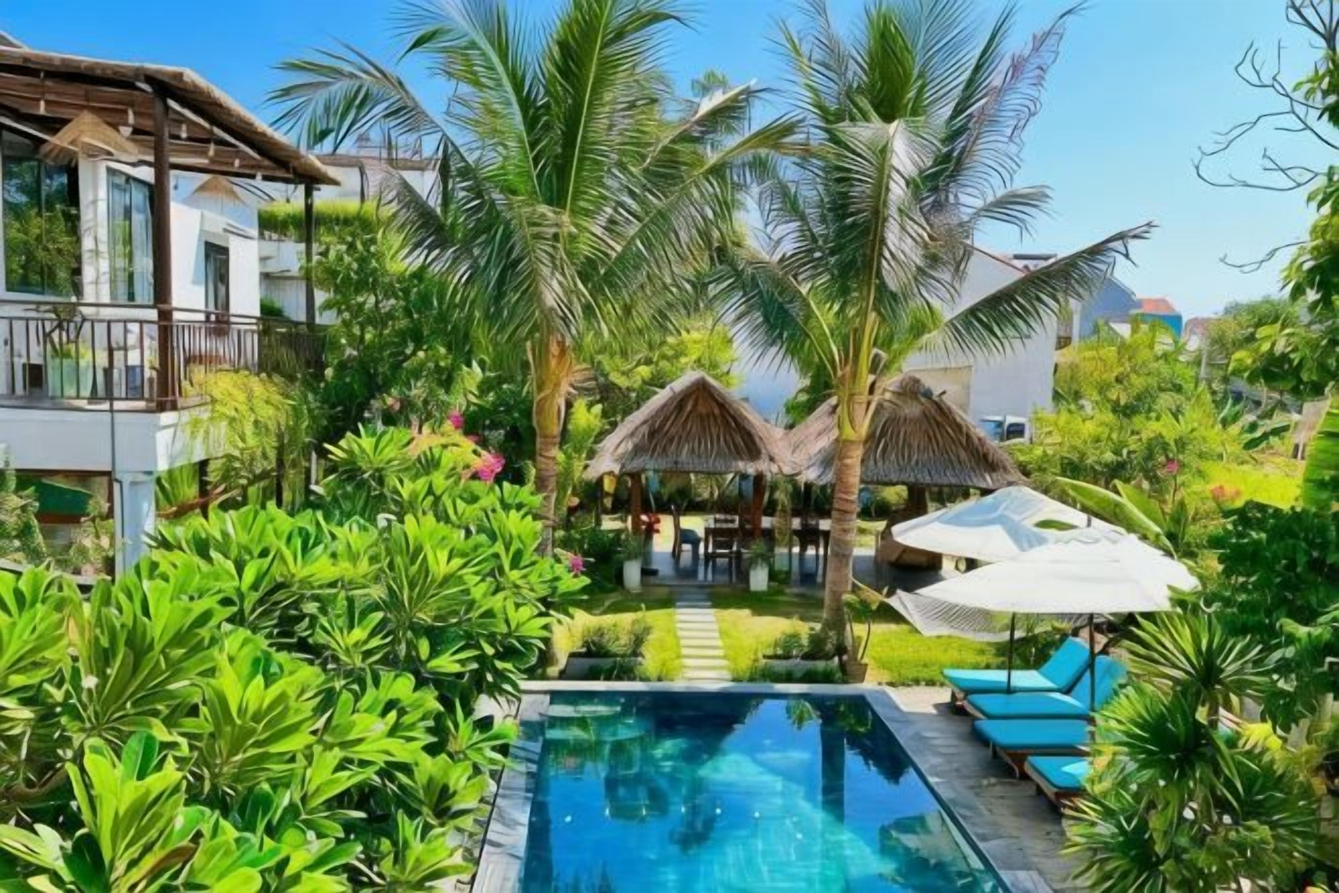 A pool surrounded by lush greenery and a thatched-roof structure.
