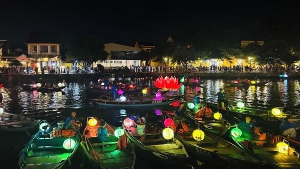 A nighttime scene with boats docked along a river, illuminated by colorful lanterns. - An Bang Garden Pool Villa (Hoi An)