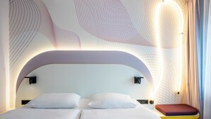Een moderne slaapkamer met een gebogen hoofdbord, een bed met wit beddengoed en een nachtkastje met een rode kussentje.
