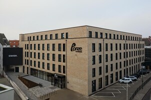 Un edificio moderno con un letrero que dice 'Force', un estacionamiento y un letrero de 'Stayery' cerca.