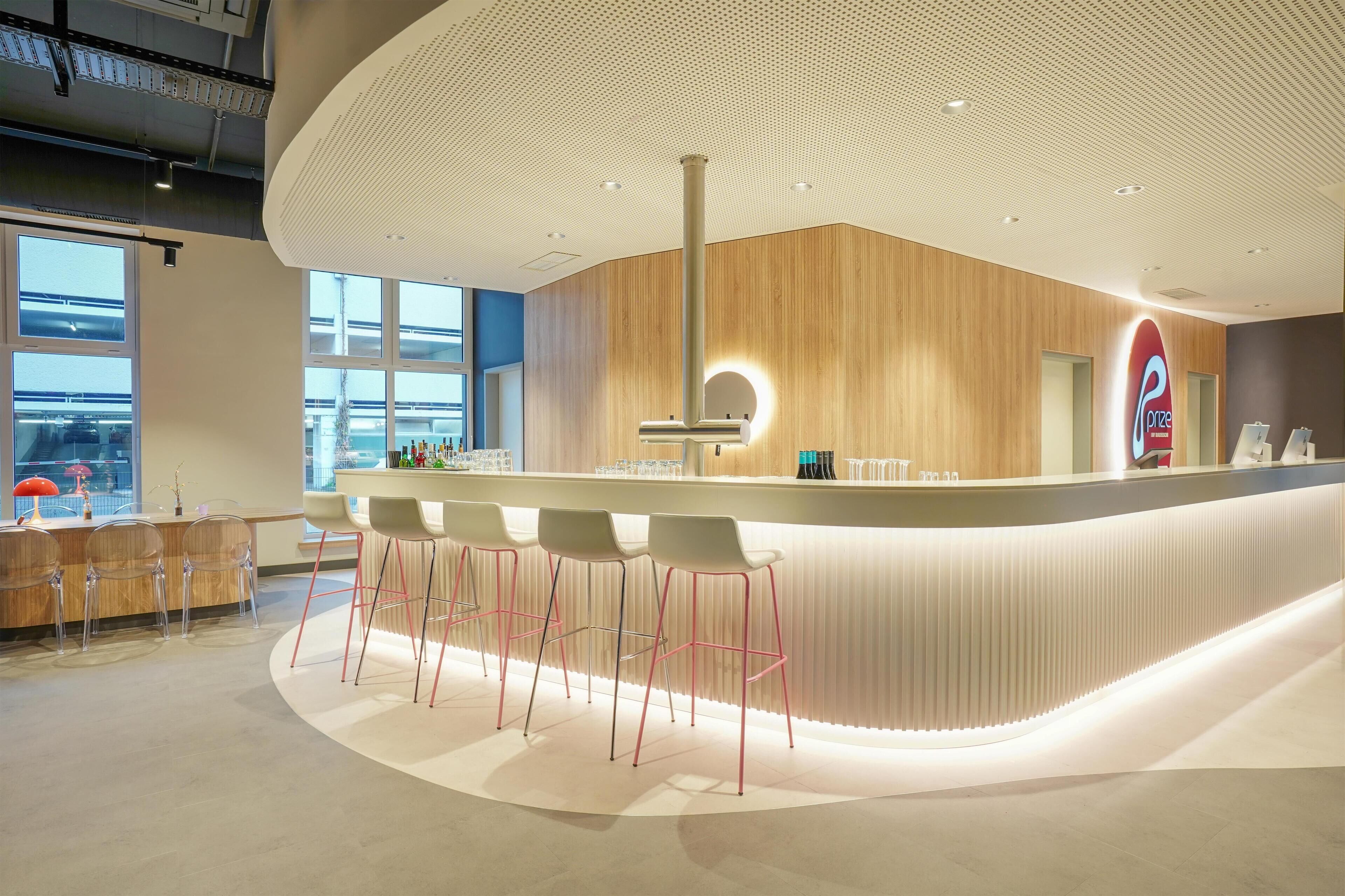 Un espace bar moderne doté d’un comptoir incurvé, de tabourets de bar et d’une grande fenêtre offrant une vue sur la ville.