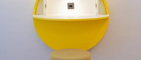 A yellow circular wall-mounted unit with a light, a small stool, and a patterned floor.