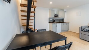 Una cucina moderna con zona pranzo, una scala e un divano.