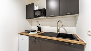 Una cocina compacta con microondas, cafetera y un refrigerador pequeño.