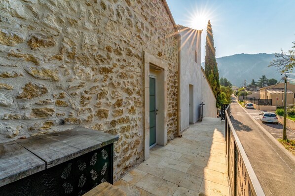 A stone building with a narrow street, a green door, and a view of a mountain.