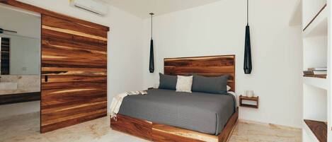 Une chambre à coucher avec une tête de lit en bois, un lit avec une literie grise, une table de chevet et une lampe suspendue.