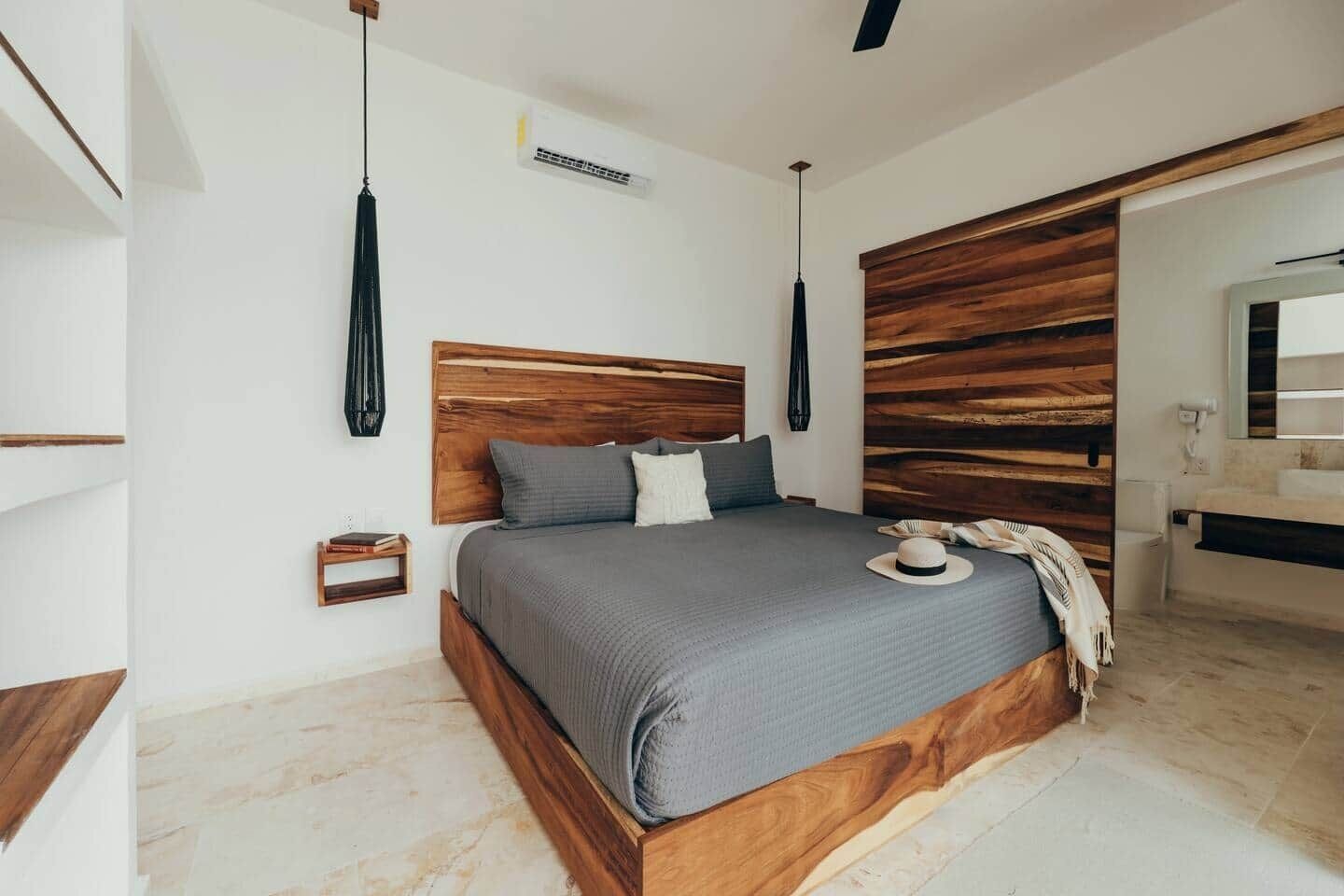 Une chambre à coucher moderne avec une tête de lit en bois, une table de chevet et un grand miroir.
