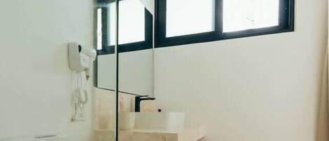 A bathroom with a toilet, a sink, a mirror, and a window.