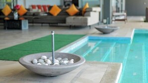 A stone bowl with pebbles and a metal stick on a tiled surface near a pool. - Aroha Seaview Villa In Nature - Private Pool (Langkawi)