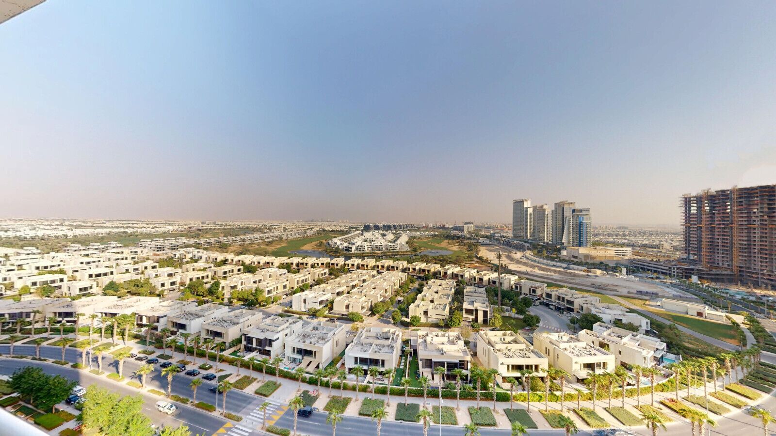 A residential area with modern apartment buildings, roads, and a distant view of high-rise buildings.