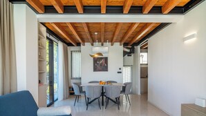 A modern living room with a blue sofa, a dining area with a table and chairs, and a kitchen in the background. - VICE VERSA-SESASIDE BOUTIQUE APARTMENTS-APP NR.1 (Punat)