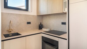 A modern kitchen with a black countertop, a gold faucet, a built-in oven, and a window above the sink. - VICE VERSA-SESASIDE BOUTIQUE APARTMENTS-APP NR.1 (Punat)