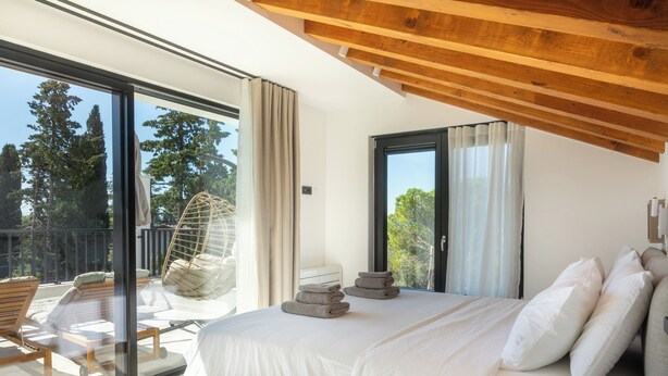 A bedroom with a large bed, a wooden ceiling, and a balcony with outdoor furniture. - VICE VERSA-SESASIDE BOUTIQUE APARTMENTS-APP NR.1 (Punat)