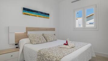A bedroom with a bed, a nightstand, a painting, and a window.
