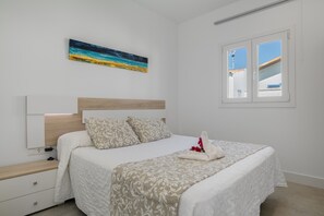 A bedroom with a bed, a nightstand, a painting, and a window.