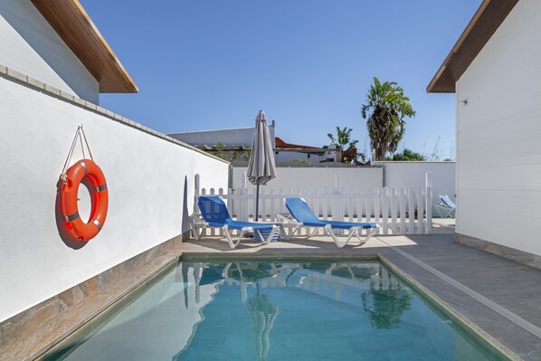 A swimming pool with lounge chairs and a life preserver.