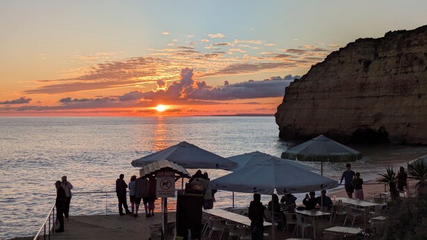 A coastal sunset view with people, outdoor seating, and a cliff. - 'Beira Mar' Carvoeiro - Modern, intimate studio -Distant Ocean View - Fast Wifi (Carvoeiro)