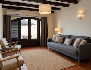 A living room with a sofa, chairs, a rug, a pendant light, and a wall-mounted lamp.