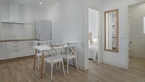 Et moderne køkken med hvide skabe, et spisebord med stole og et stort spejl på væggen.