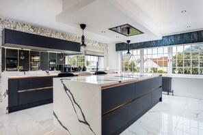 Una cocina moderna con una isla grande, muebles negros y vistas al exterior.