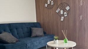 Ett modernt vardagsrum med en blå soffa, ett runt träbord och dekorativ väggkonst.