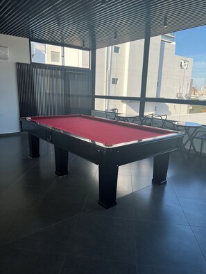 Una mesa de billar en una habitación con vistas a edificios.