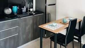 Ett kompakt kök med kylskåp, spis och ett litet matbord med stolar.