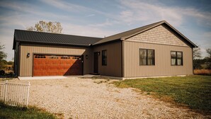 A modern single-story house with a garage, a covered driveway, and a well-maintained lawn.
